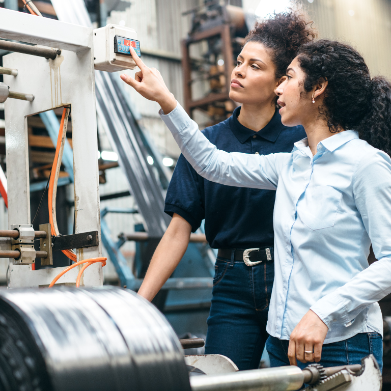 Dos mujeres jóvenes trabajando en la sala de máquinas de una empresa 
